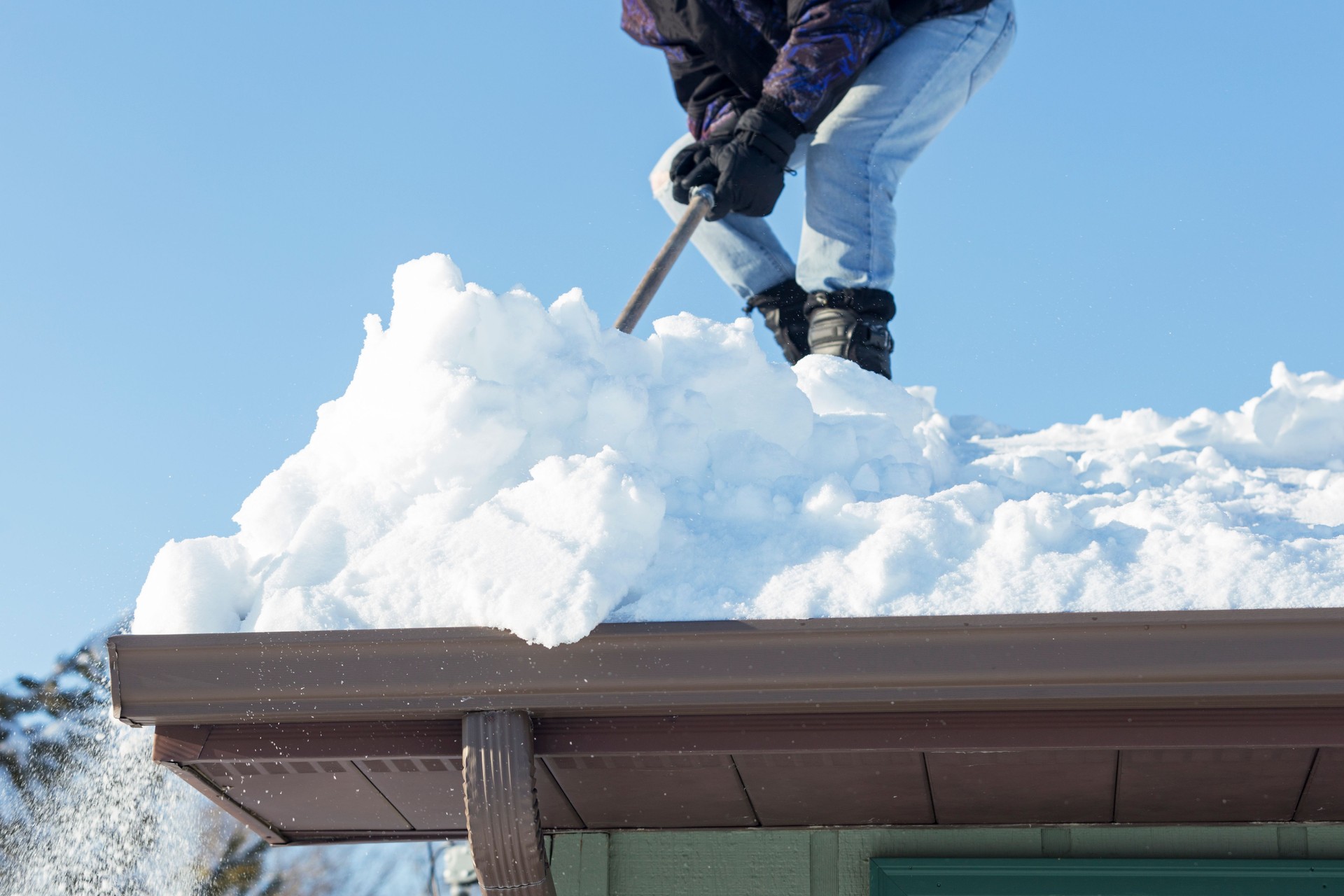 Man Shoveling Deep Snow Off a Rooftop